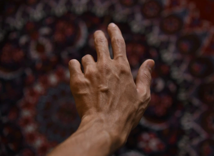 A hand reaches out against a patterned background.